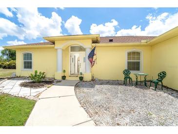 Charming single-story home featuring a welcoming front entrance with decorative columns and outdoor seating at 6158 Cavan St, Englewood, FL 34224