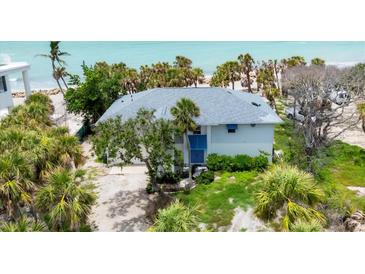 Coastal home featuring lush tropical landscaping, a gray roof, and a serene view of the beach and ocean at 7420 Manasota Key Rd, Englewood, FL 34223
