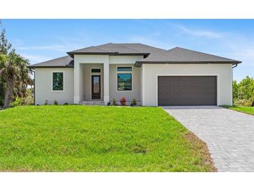 Beautiful one-story home featuring a well-manicured lawn and a modern two-car garage at 8105 Antwerp Cir, Port Charlotte, FL 33981