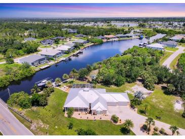 Stunning aerial view of waterfront home with pool, lush landscaping, boat dock and seawall at 8127 Consul St, Port Charlotte, FL 33981