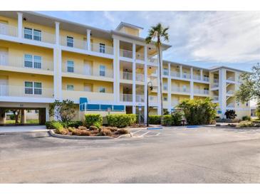 Condominium complex featuring a yellow facade, white railings, covered parking and lush landscaping at 8411 Placida Rd # 404, Placida, FL 33946