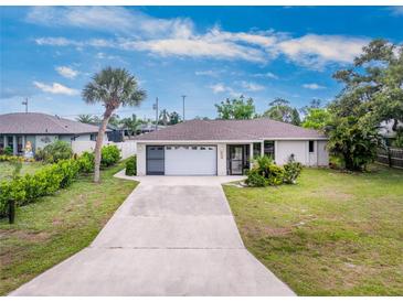 Charming single-story home featuring a two-car garage and a well-manicured front yard with mature trees at 1337 Le Pera Rd, Englewood, FL 34223