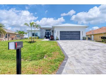 Beautiful single-story home with a lush green lawn, stone accents, and a gray paved driveway at 15610 Staunton Cir, Port Charlotte, FL 33981