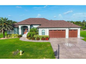 Charming single Gathering home showcasing a three-car garage, lush landscaping, and a well manicured green lawn at 204 W Pine Valley Ln, Rotonda West, FL 33947