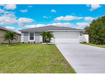 Charming single-story home with a well-maintained lawn, mature palm trees, and a two-car garage at 271 Antis Dr, Rotonda West, FL 33947