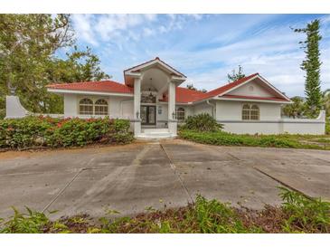 Stunning home featuring a red-tiled roof, arched windows, and a grand entrance, surrounded by lush landscaping at 365 Capstan Dr, Placida, FL 33946