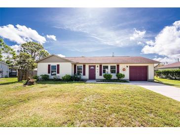 Charming single-story home featuring a well-manicured lawn, attached garage, and delightful curb appeal at 4399 Mundella Cir, Port Charlotte, FL 33948