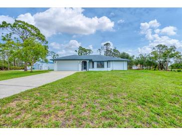 Charming single-story home featuring a well-maintained lawn, attached garage, and inviting front entrance at 5412 Ulysses St, Port Charlotte, FL 33981