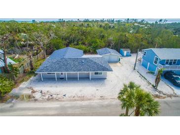 Charming single-story home with a large yard, lush landscaping, and a detached garage at 608 Saint Judes Dr, Longboat Key, FL 34228