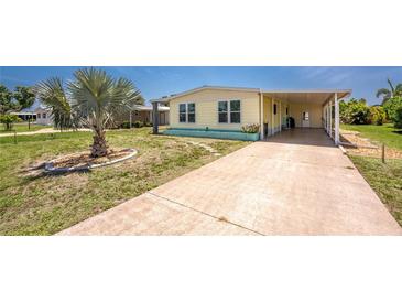 Charming yellow home featuring a well-manicured yard, large driveway, and a convenient covered parking area at 6293 Sparrow Ln, Englewood, FL 34224
