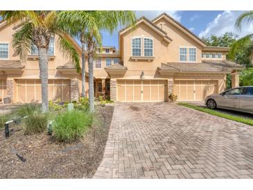 Inviting townhome exterior featuring a multi-car garage, brick driveway, and tropical landscaping including palms at 8228 Villa Grande Ct, Sarasota, FL 34243