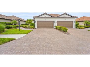 Charming villa with a two-car garage, brick driveway and tile roof, complemented by neat landscaping at 10258 Morning Mist Ln, Sarasota, FL 34241