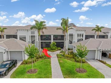 Beautiful building exterior with lush landscaping and private garages at 12550 Galapagos Ct # 104, Venice, FL 34293