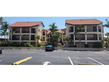 Condominium complex with a two-story building, parking, and surrounding palm trees at 1760 Gulf Blvd # 511, Englewood, FL 34223