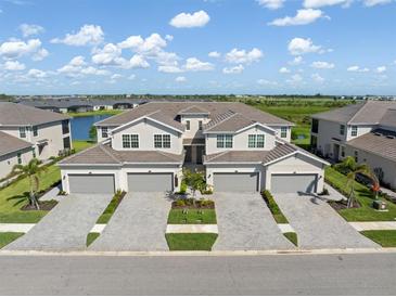 Aerial view of multi-Gathering homes with garages and manicured landscaping near a scenic lake and lush green spaces at 17605 Boracay Ct # 201, Venice, FL 34293