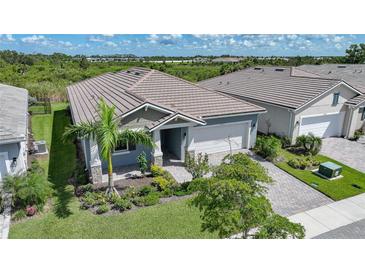 Charming home with a well-manicured lawn, lush landscaping, and a tile roof at 17921 Grand Prosperity Dr, Venice, FL 34293
