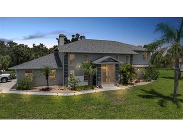 Stately two-story home featuring lush landscaping, a portico entrance, and mature palm trees at 196 Lecturn St, Port Charlotte, FL 33954