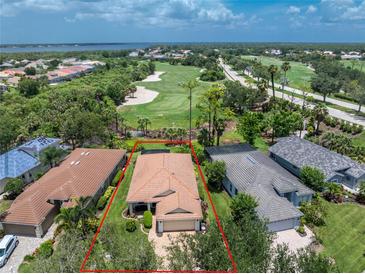 Expansive aerial view of property showcasing lush landscaping, golf course, and serene lake views at 3207 Village Ln, Port Charlotte, FL 33953