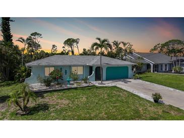 Charming single-story home with a well-manicured lawn, tropical landscaping and turquoise accents at 55 Mark Twain Ln, Rotonda West, FL 33947