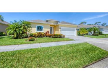 Charming home featuring a well-manicured lawn, lush landscaping, and a welcoming two-car garage at 576 Box Elder Ct, Englewood, FL 34223