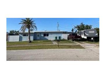 Single story home with a lawn, palm tree and an RV parked in the driveway at 700 Floral Ln, Port Charlotte, FL 33952