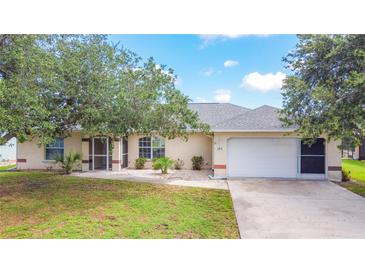 Charming single-story home with a well-maintained lawn, mature trees, and an attached two-car garage at 104 Mark Twain Ln, Rotonda West, FL 33947