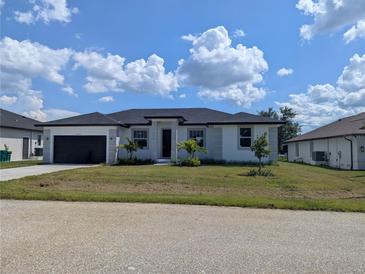 Charming one-story home with well-manicured front lawn and attached two car garage, plus some decorative palms at 14149 Whittier Ln, Port Charlotte, FL 33981