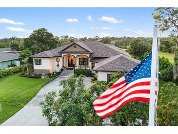 Elegant home exterior showcasing manicured lawn, mature trees, and a charming entrance at 1415 Bayshore Dr, Englewood, FL 34223