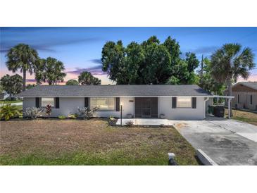 Charming single-story home boasting a well-manicured lawn, enhanced by lush landscaping and mature palm trees at 1730 Bluebird Ln, Englewood, FL 34224