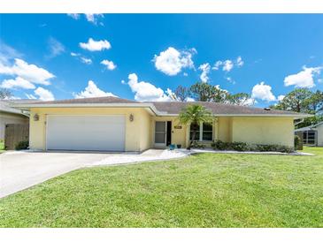 Charming single-story home with a manicured lawn, light yellow exterior, and a well-maintained two car garage at 4221 Ulster Ave, North Port, FL 34287