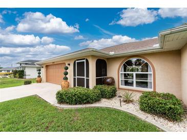 Charming home with a well-manicured lawn, a decorative landscape, and a tan-colored exterior at 4227 Winona St, Port Charlotte, FL 33948