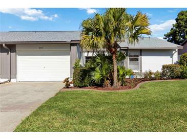 Charming home featuring a well-manicured lawn, mature palm tree, and an attached single-car garage at 609 Deerwood Ave, Englewood, FL 34223