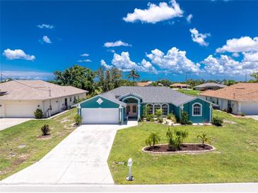 Charming single-story home with a vibrant turquoise exterior, well-manicured lawn, and a spacious driveway at 926 Boundary Blvd, Rotonda West, FL 33947