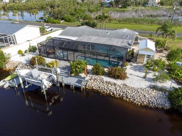Aerial view of a home featuring a screened pool, dock, and canal access at 1030 Haste Ln, Englewood, FL 34223