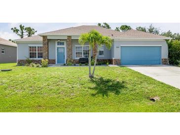 Charming single-story home featuring a well-manicured lawn, stone accents, and a bright blue garage door at 9151 Melody Cir, Port Charlotte, FL 33981