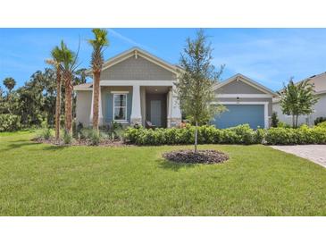 Charming one-story home with gray siding, blue door, and landscaped lawn at 7434 Sea Manatee St, Parrish, FL 34219