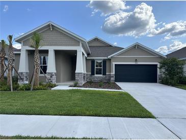 Charming single-story home boasts stone accents, a dark garage door, and freshly landscaped front yard at 17434 Crisp Apple Ln, Land O Lakes, FL 34638