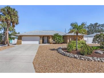 Charming single-story home featuring desert landscaping, a two-car garage, and mature palm trees at 909 Dawn St, Venice, FL 34285