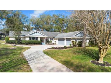 Charming ranch-style home with a long driveway, mature landscaping, and a two-car garage at 12631 Timber Run, Dade City, FL 33525