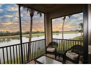 Relaxing balcony with wicker furniture overlooking a serene lake and palm trees at 7005 River Hammock Dr # 207, Bradenton, FL 34212