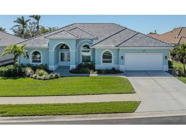 Charming single-story home with a manicured lawn, tile roof, arched windows, and a two-car garage at 519 Purslane Pt, Venice, FL 34293