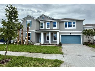 Charming two-story home features a blue garage door, blue shutters, a manicured lawn, and a classic facade at 9572 Brave Buck Ave, Land O Lakes, FL 34638