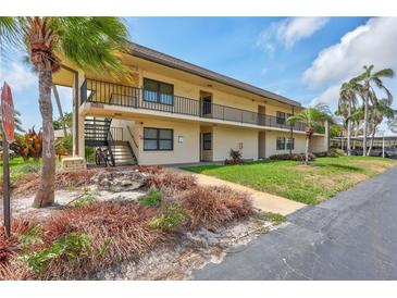 Two-story condo building with tropical landscaping, exterior stairs, and a view of the parking area at 12300 Vonn Rd # 1102, Largo, FL 33774