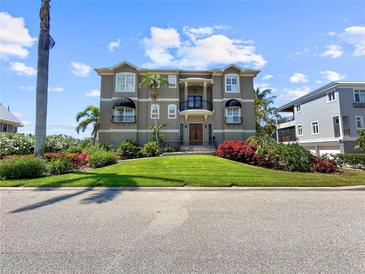 Stunning three-story home featuring manicured landscaping, dual balconies, and a grand entrance at 7020 Hawks Harbor Cir, Bradenton, FL 34207