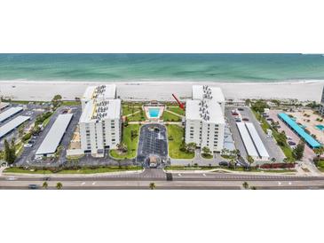 An aerial view of the beachfront condo buildings, swimming pool, parking lot, and meticulously kept grounds at 1400 Gulf Blvd # 701, Clearwater Beach, FL 33767