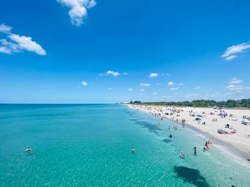 Beautiful beach scene with crystal-clear turquoise water and soft white sand under a bright blue sky at 401 Sunset Dr, Venice, FL 34285