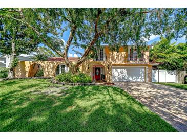 Two-story home with a well-manicured lawn, mature trees, and brick driveway at 16601 W Course Dr, Tampa, FL 33624
