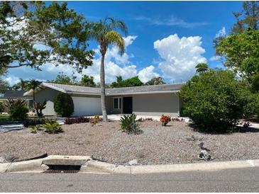 Well-maintained single-story home featuring a grey facade, complemented by a lush palm tree in the front yard at 4571 Clearwater Harbor S Dr, Largo, FL 33770