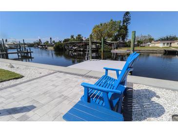 Inviting backyard with waterfront views and a dock, complete with comfortable Adirondack chairs at 817 Blue Heron Blvd, Ruskin, FL 33570