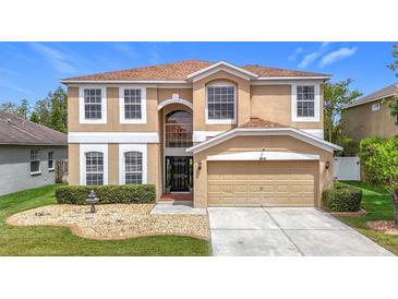 Charming two-story tan home with a well-manicured lawn and a two-car garage at 18441 New London Ave, Land O Lakes, FL 34638